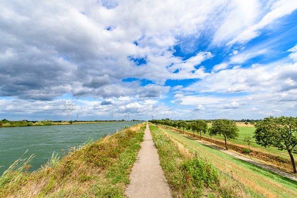 Eine asphaltierte Straße über den Deich neben dem Juliana-Kanal in Maasgouw, die sich hervorragend zum Radfahren eignet