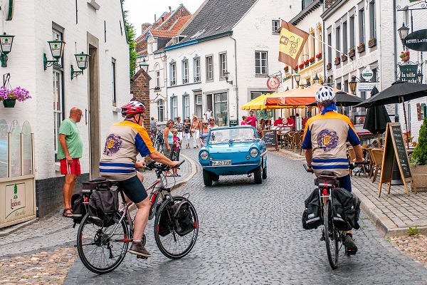 Radfahrer im Zentrum von Thorn, während sich ein Oldtimer nähert