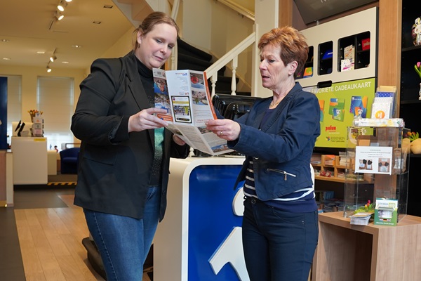 Ein Mitarbeiter des VVV Roermond hilft einem Kunden, indem er ihm etwas auf der Karte zeigt