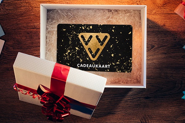 Eine Geschenkkarte liegt in einer offenen Schachtel mit rotem Band auf einem Holztisch.